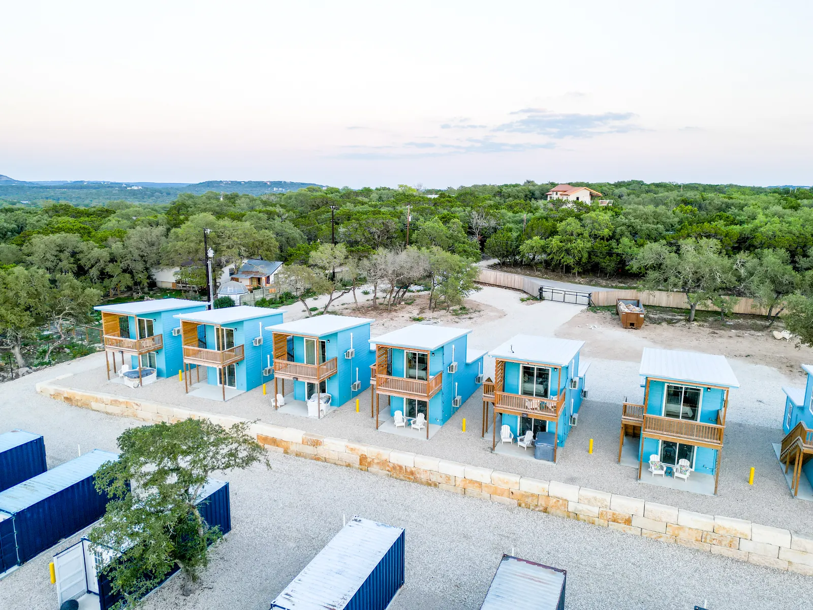 Row of two-story container homes with private decks and outdoor seating at The Container Retreat