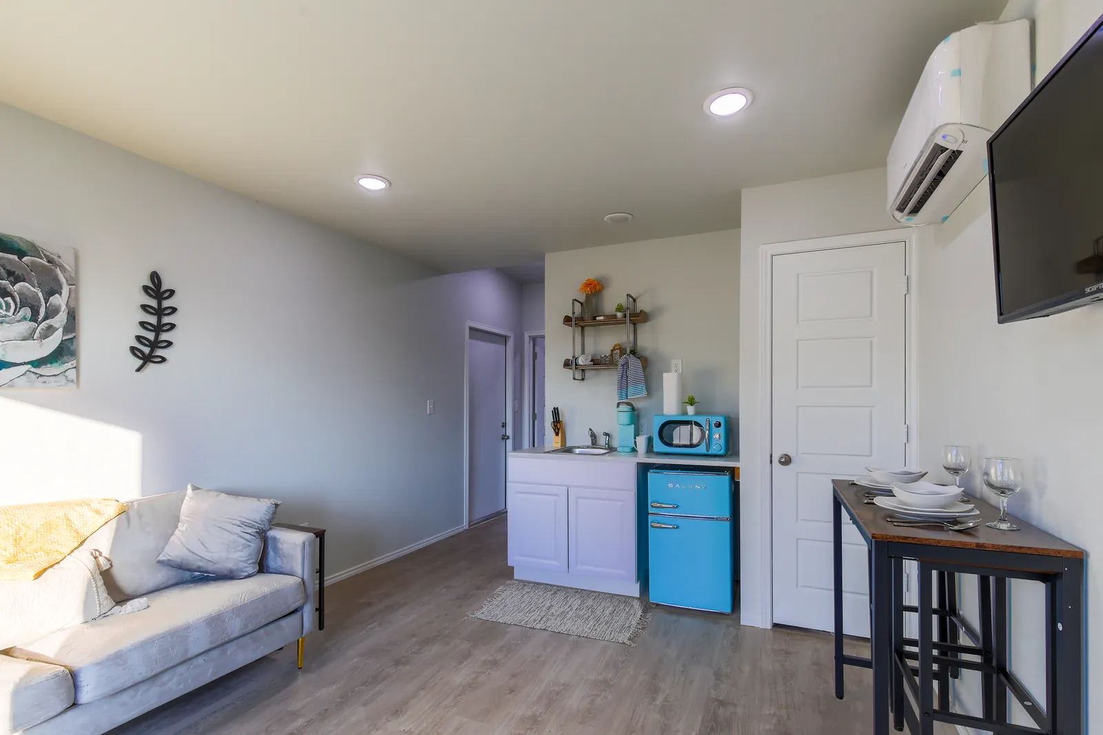 Open-plan furnished container home with living area and kitchenette